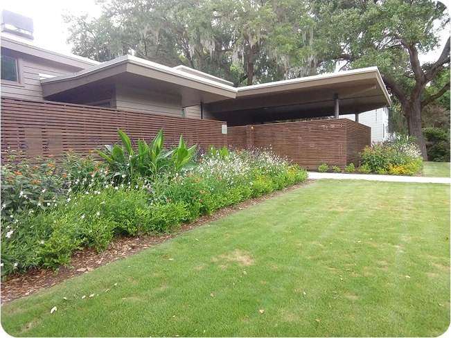 A serene walkway featuring a pergola overhead and a small, well-maintained garden alongside.