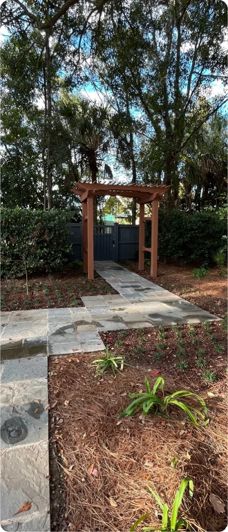A serene walkway featuring a pergola overhead and a small, well-maintained garden alongside.