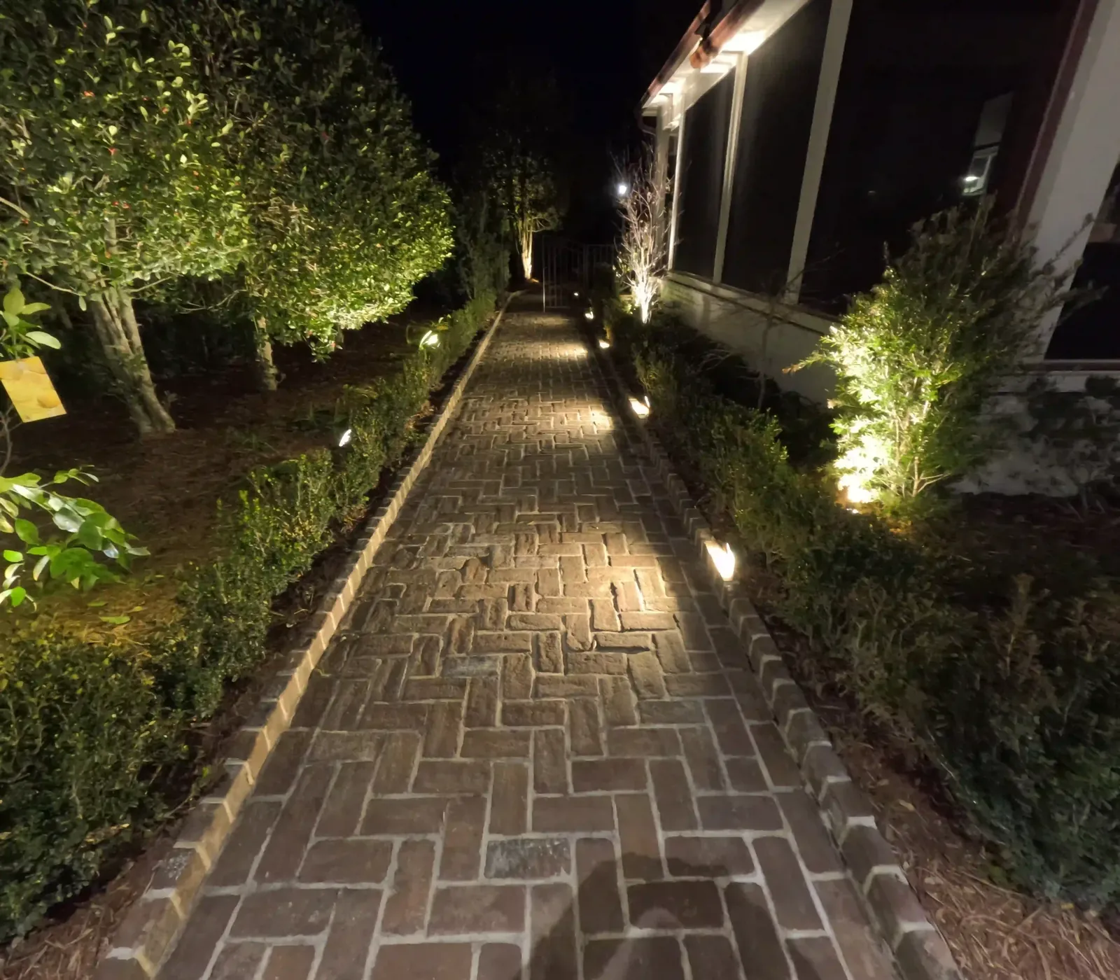 Path lighting along a brick walkway in Charleston, SC Brick herringbone walkway lit by low voltage path lights at night in Charleston, SC