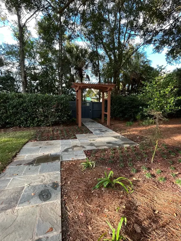 Bluestone pathway and new planting beds beneath a wooden arbor in James Island, SC
