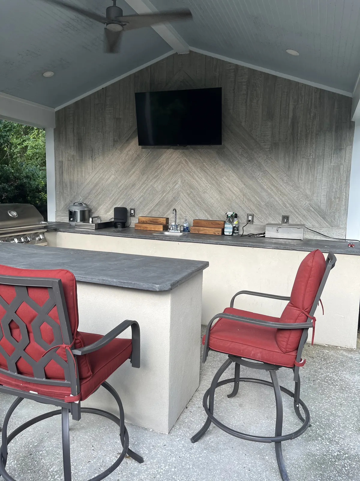 Outdoor kitchen with concrete countertops, acrylic stucco and a patterned tile back wall with a TV Outdoor kitchen with concrete countertops, acrylic stucco and a patterned tile back wall with a TV