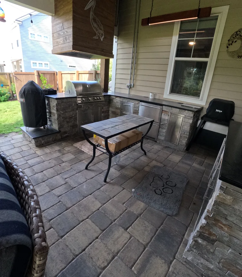 Covered porch with an outdoor kitchen and fireplace seating in Summerville, SC