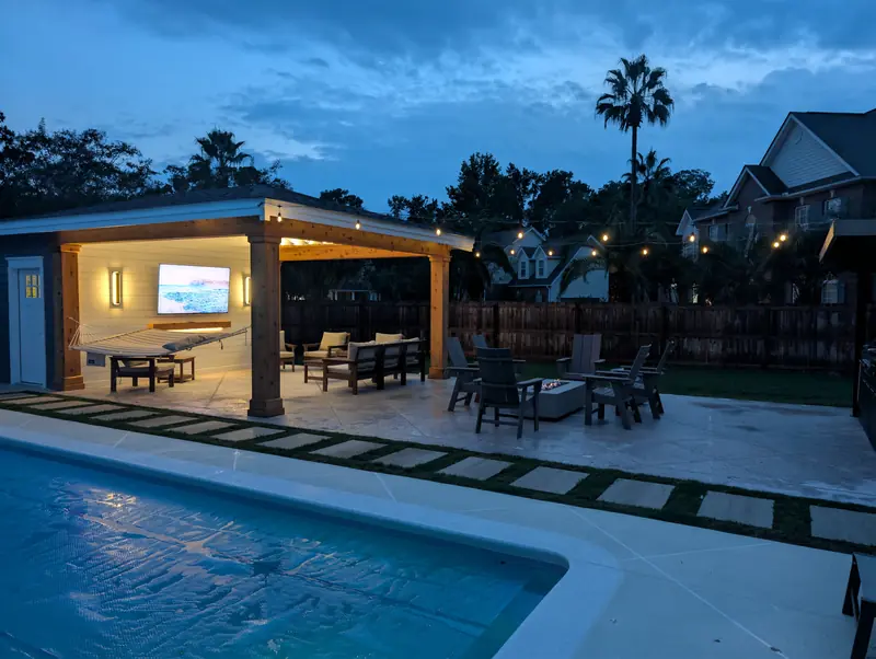 Covered pool cabana lit at night with bistro string lights over the pool in West Ashley, SC